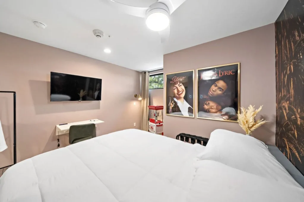 Cinema themed hotel room in Houston showcasing vintage movie posters, a wall-mounted flat-screen TV, a writing desk, and a decorative popcorn machine.